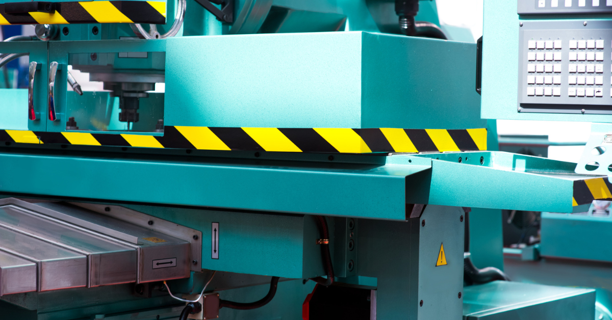 Teal hydraulic press with yellow and black safety paint around middle